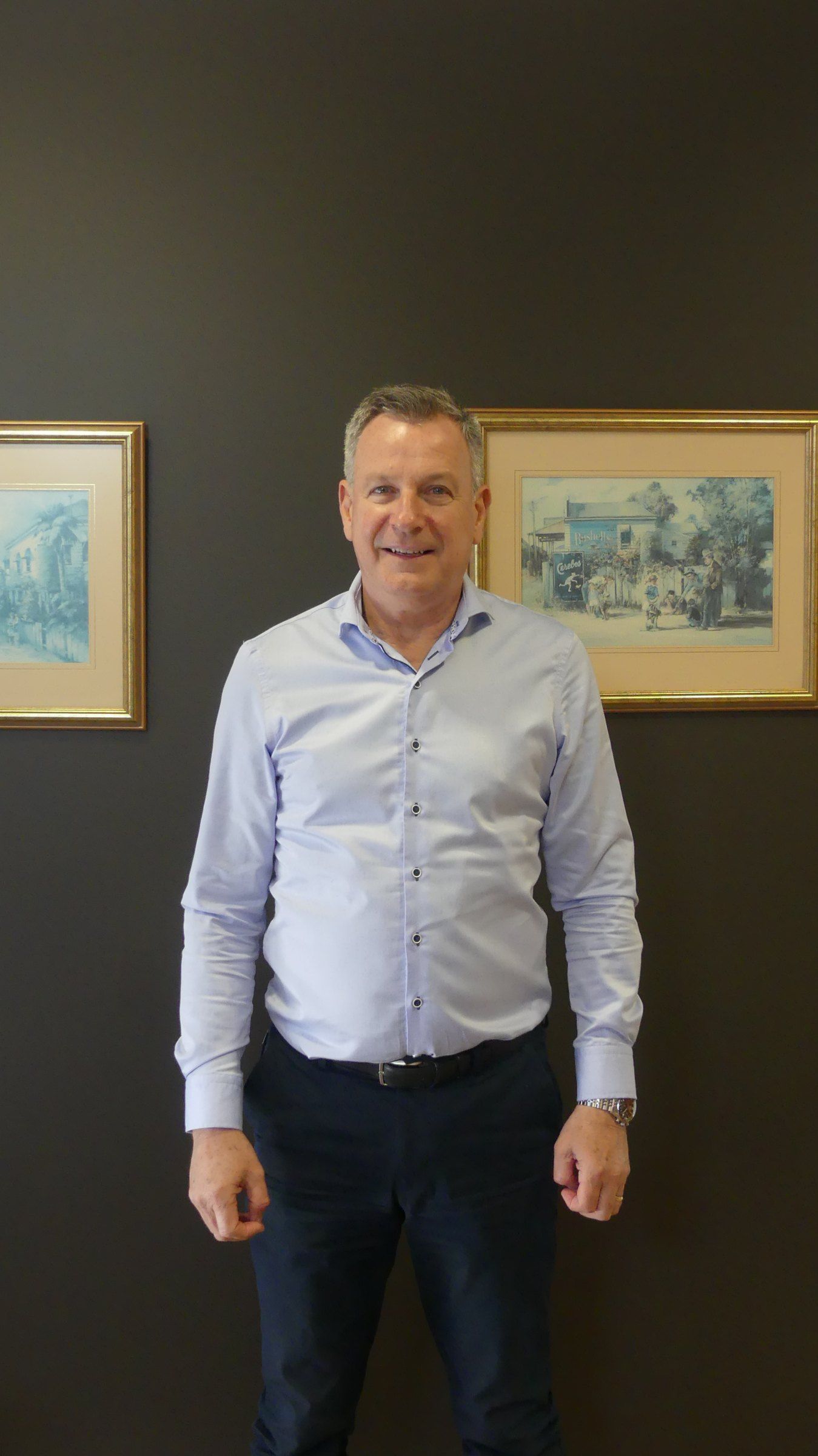 Martin Welsford in the Welsford office, in front of framed watercolours