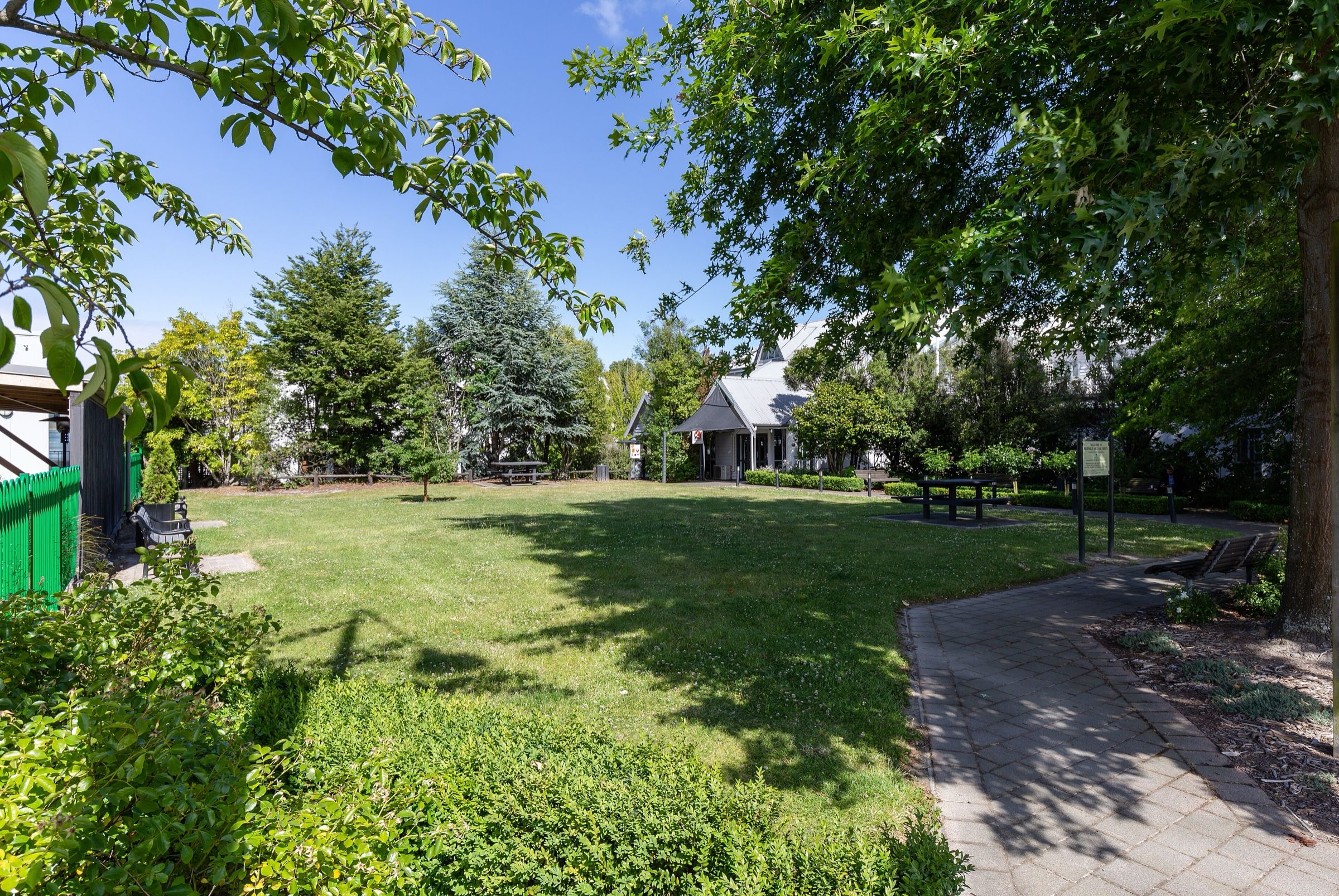 Merivale Village Green on a summer day, a lawn and path under large trees